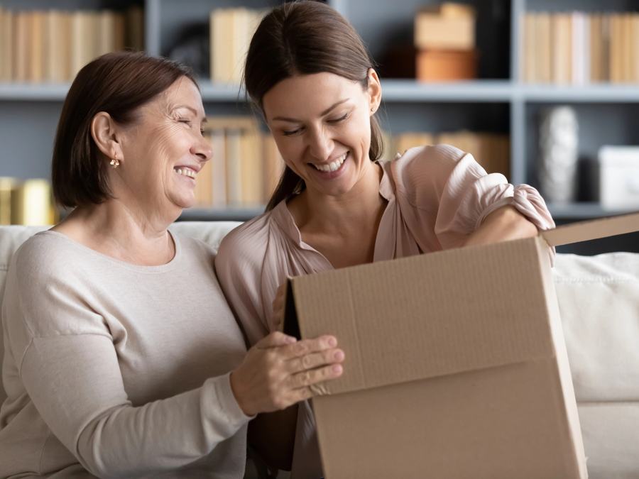 Mother and adult daughter smiling over a packed box